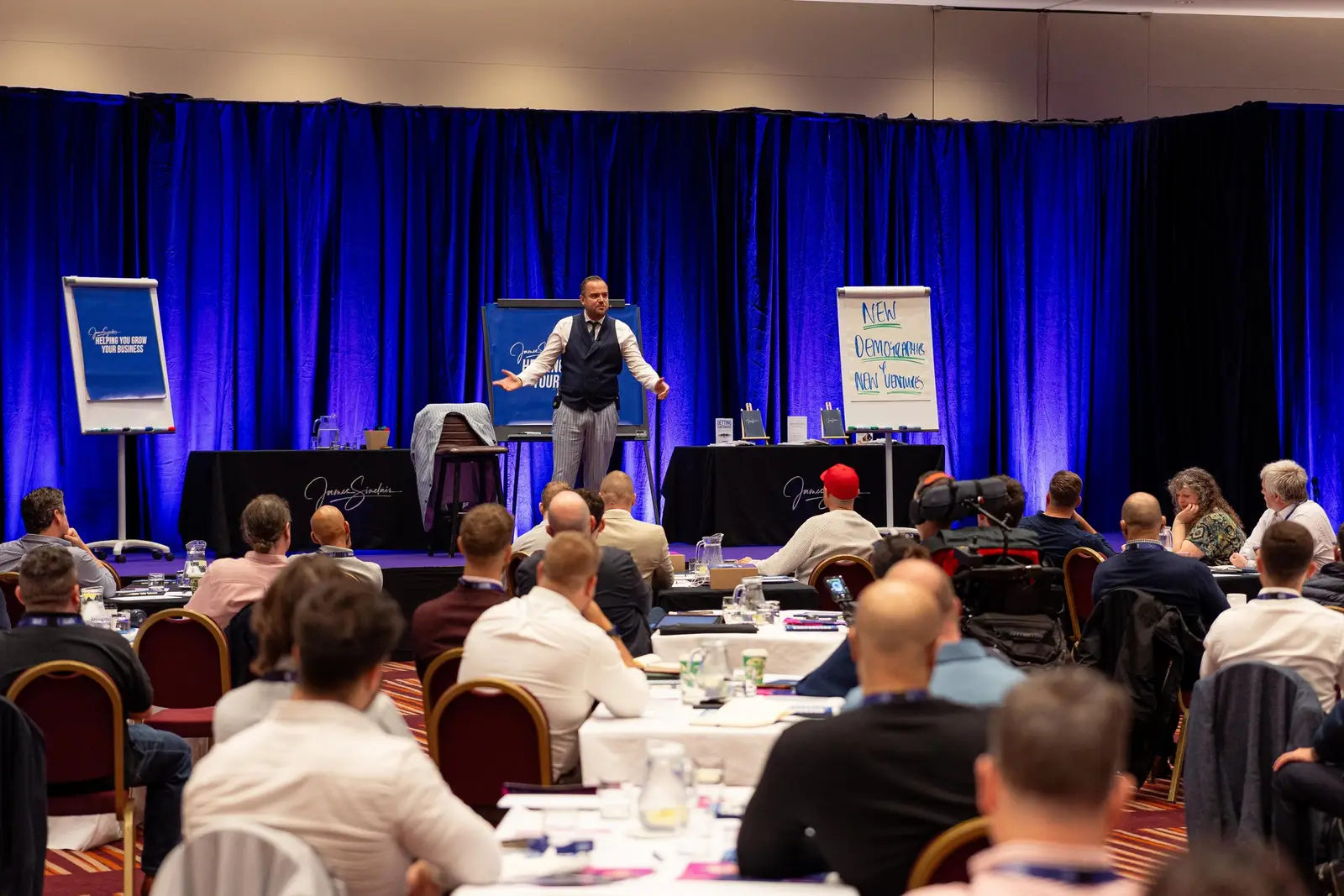James on stage at the Business Masterclass in front of a packed room